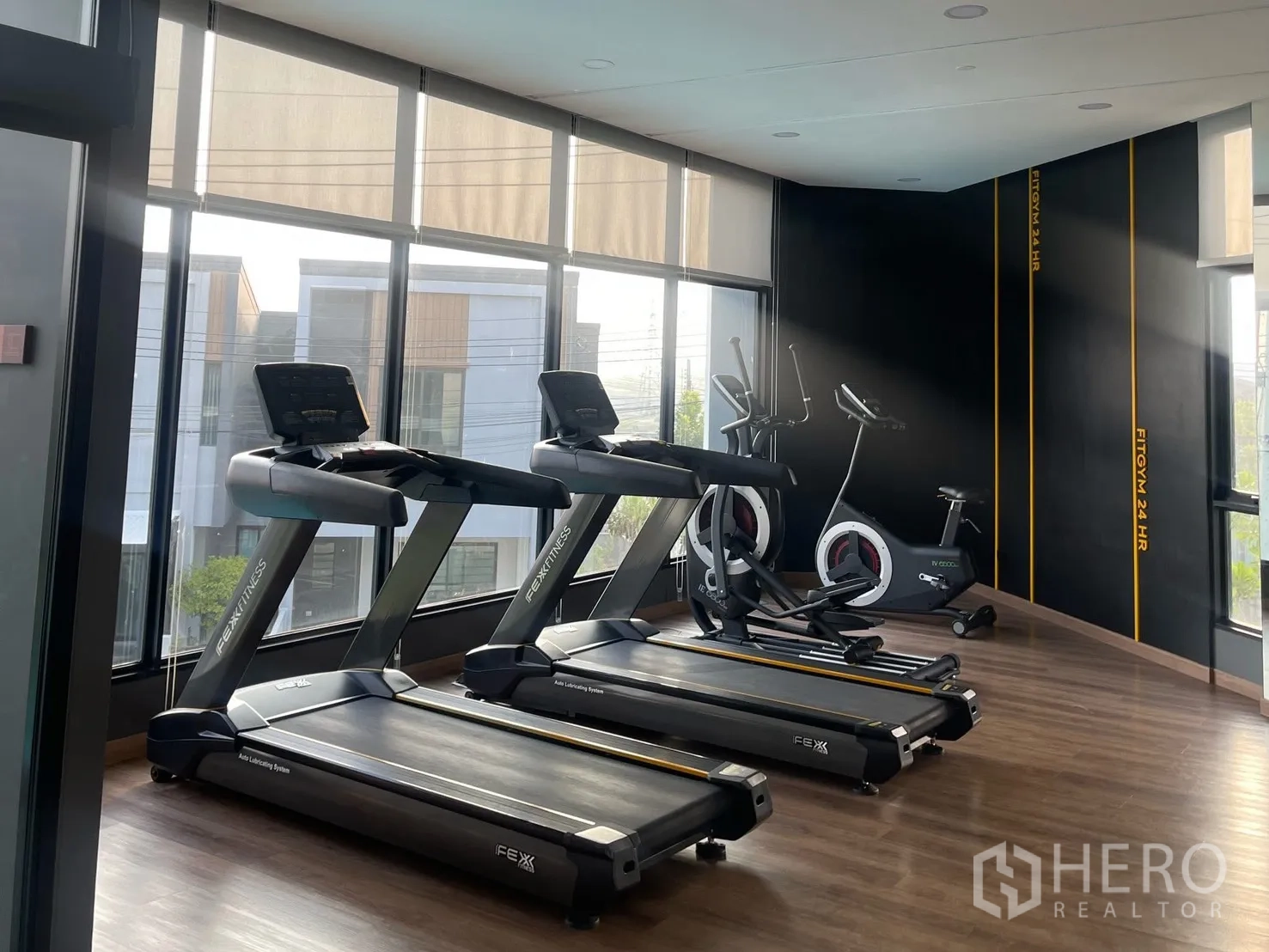 Townhouse for rent in Bang Phli, Samut Prakan - On-site fitness room featuring treadmills and stationary bikes beside floor-to-ceiling windows.