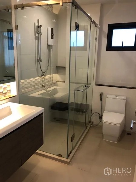 Detached House for rent or sale in Bang Kapi, Bangkok - Contemporary bathroom featuring a glass-enclosed shower, vanity and toilet.