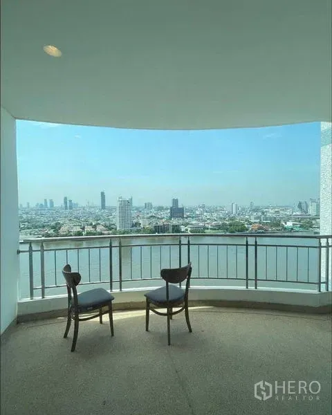 คอนโด ขายในBangkok - ระเบียงกึ่งในร่มมีเก้าอี้สองตัวรับวิวแม่น้ำและเมือง