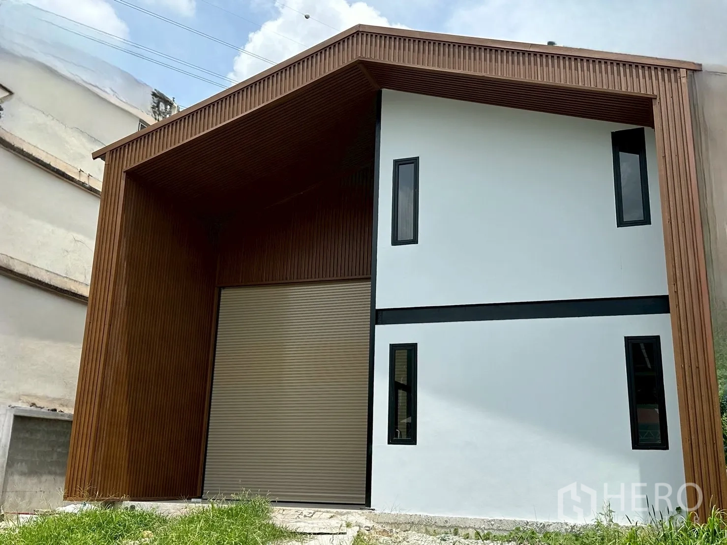 Warehouse for rent in Suan Luang, Bangkok - Modern new warehouse exterior in Suan Luang with wood-clad facade and tall roller shutter door.