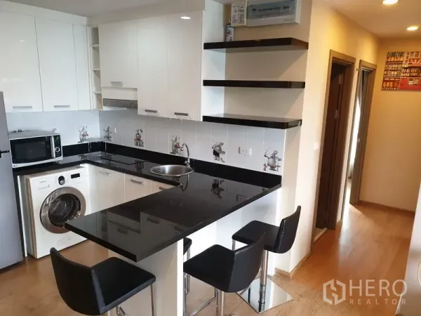 Condominium for rent in Watthana, Bangkok - Compact white kitchen with black granite countertop, bar seating and washer.