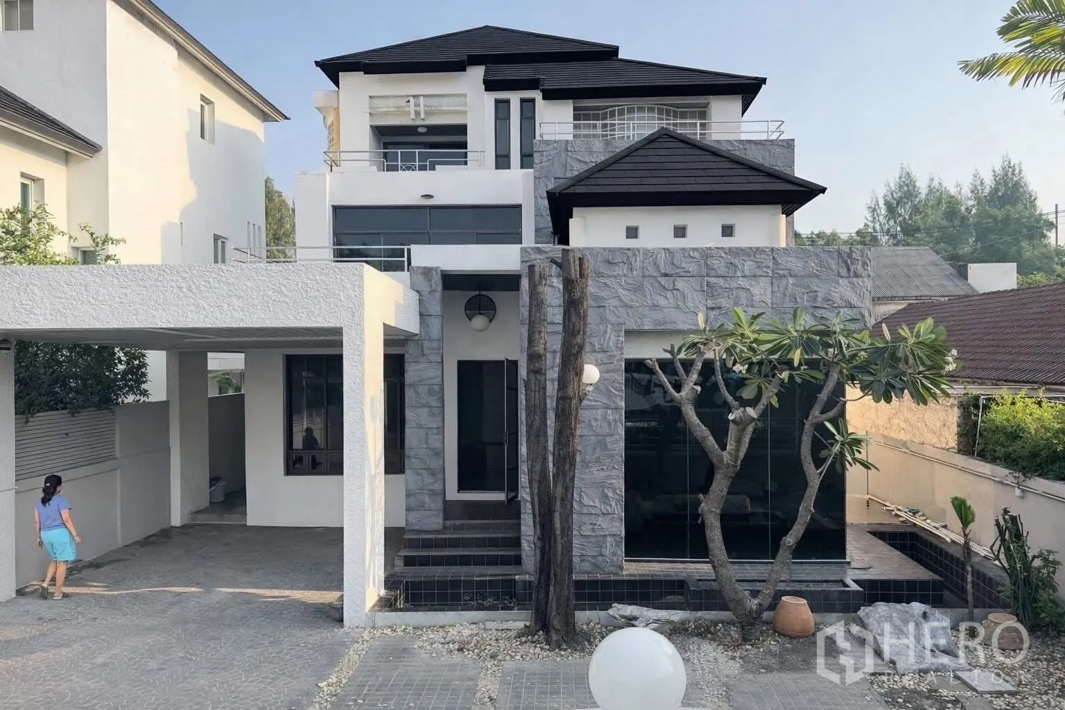 บ้านเดี่ยว for rent in Suan Luang, Bangkok - มุมมองด้านหน้าบ้าน ผนังแต่งหิน ทางรถเข้า และต้นลีลาวดีขนาดใหญ่