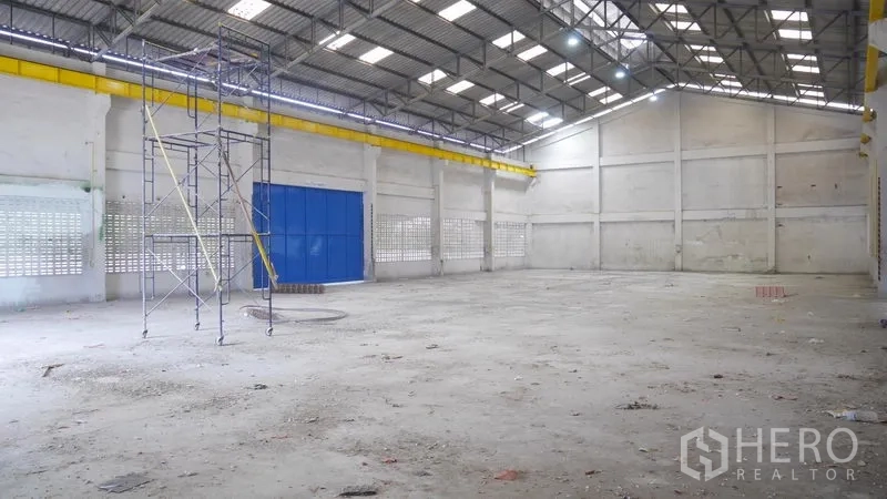 Factory for rent in Khlong Sam Wa, Bangkok - Spacious factory floor with ventilation block walls, metal roof and a maintenance scaffold.