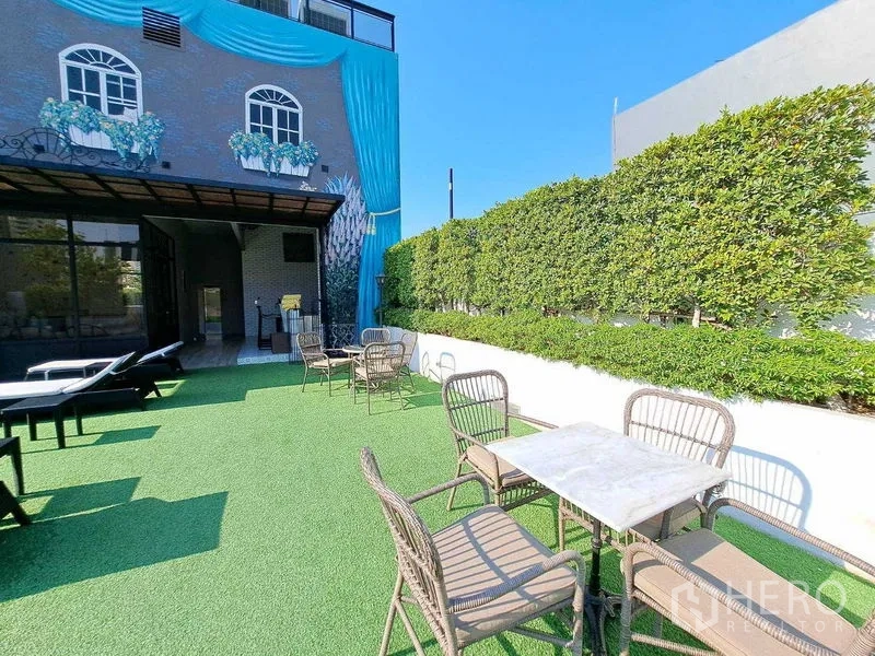 พื้นที่ขายปลีก ให้เช่าในWatthana, Bangkok - เทอเรซสวนกลางแจ้ง โต๊ะเก้าอี้หวาย สนามหญ้าเทียมและแนวรั้วพุ่มไม้