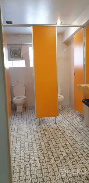 零售空间 出租在Chatuchak, Bangkok - 卫生间设黄色隔断、花纹地砖与分隔坐便。