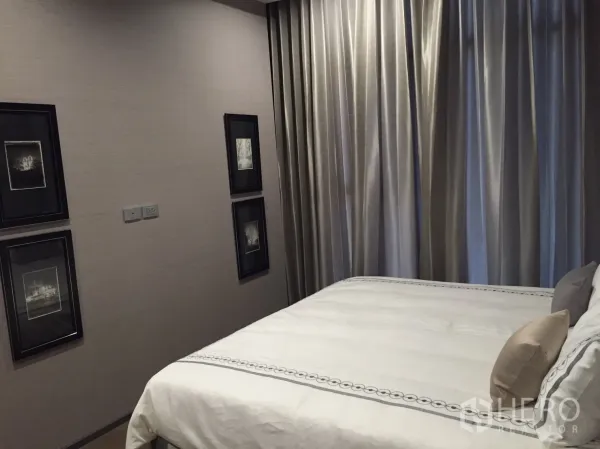 公寓 出租在Bang Rak, Bangkok - 温馨卧室，白色床品、墙面装饰画与到顶遮光窗帘。