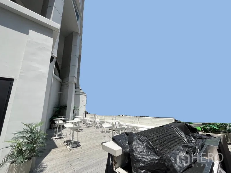 零售空间 出租在Ratchathewi, Bangkok - 室外露台，白色桌椅与现代建筑立面相邻。