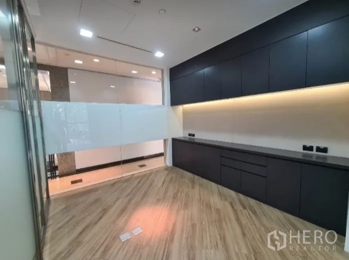 สำนักงาน ให้เช่า - โซนทำงานพร้อมตู้บิวท์อินสีเข้ม ไฟใต้ตู้ และพื้นไม้