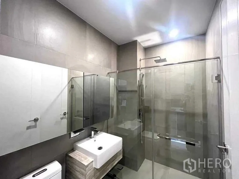 Condominium for sale - Contemporary bathroom with glass-enclosed rain shower, vanity sink and mirrored cabinets.