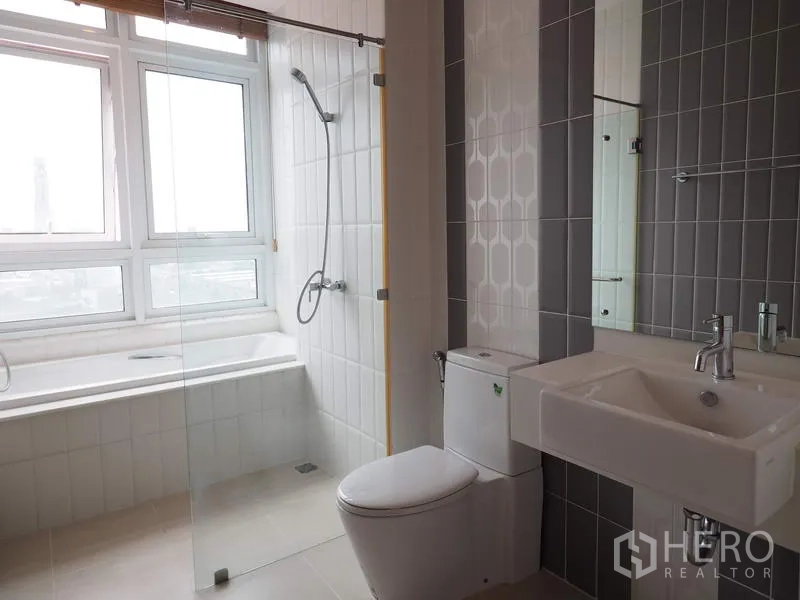 Condominium for rent in Ratchathewi, Bangkok - Modern bathroom with soaking tub by the window, glass shower and square basin vanity.