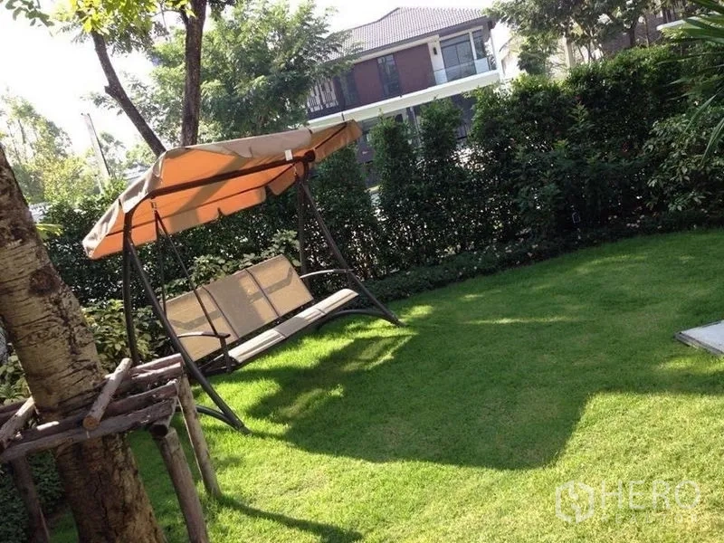 Detached House for sale in Prawet, Bangkok - Shaded lawn with a canopy swing seat under trees.