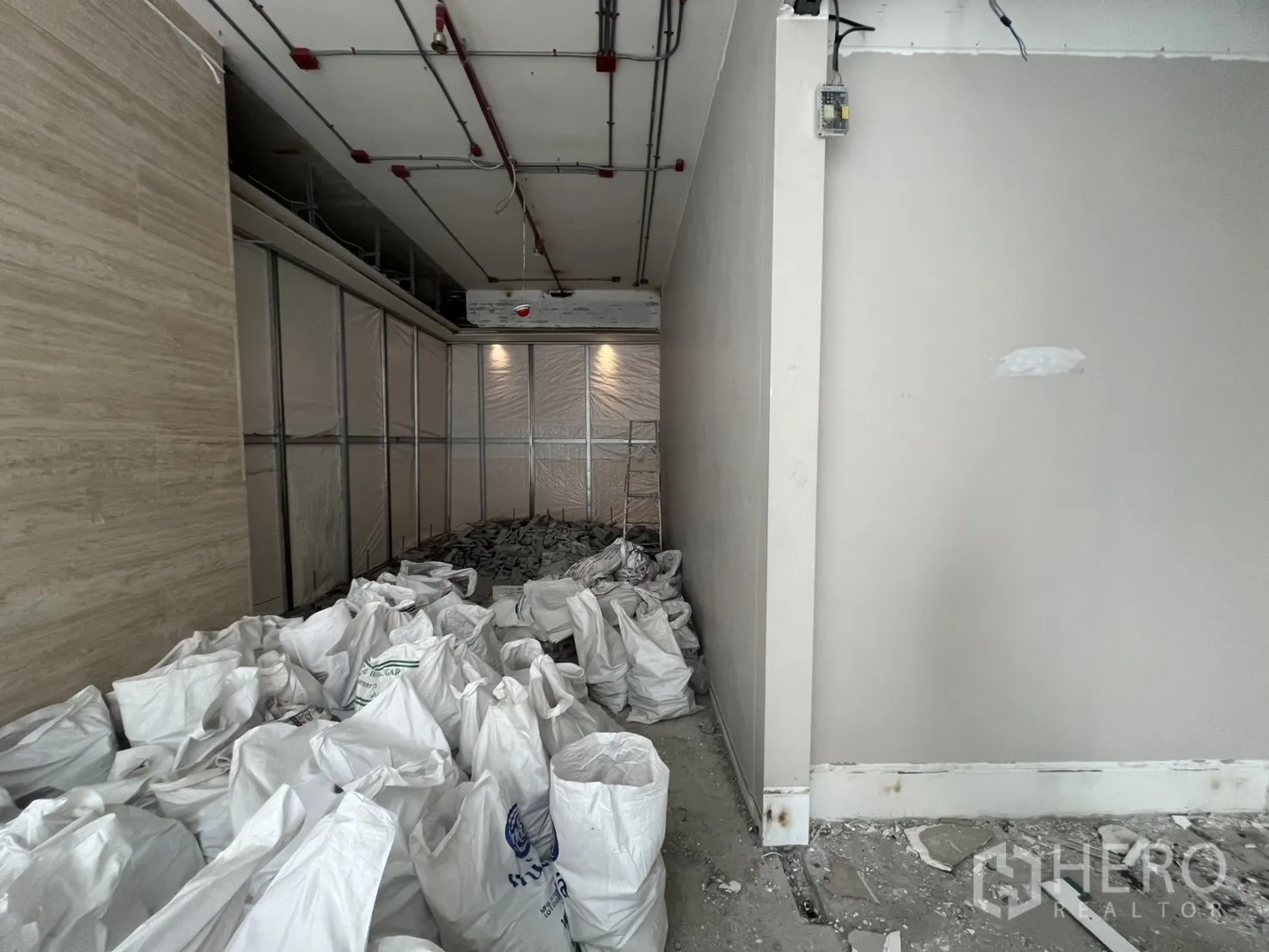 零售空间 出租 - 单元入口过道，堆放建筑垃圾袋与临时隔墙。