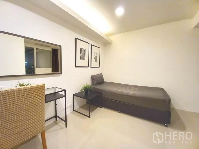 公寓 出租在Khlong Toei, Bangkok - 第二卧室配单人床、书桌、墙面装饰画和边几。