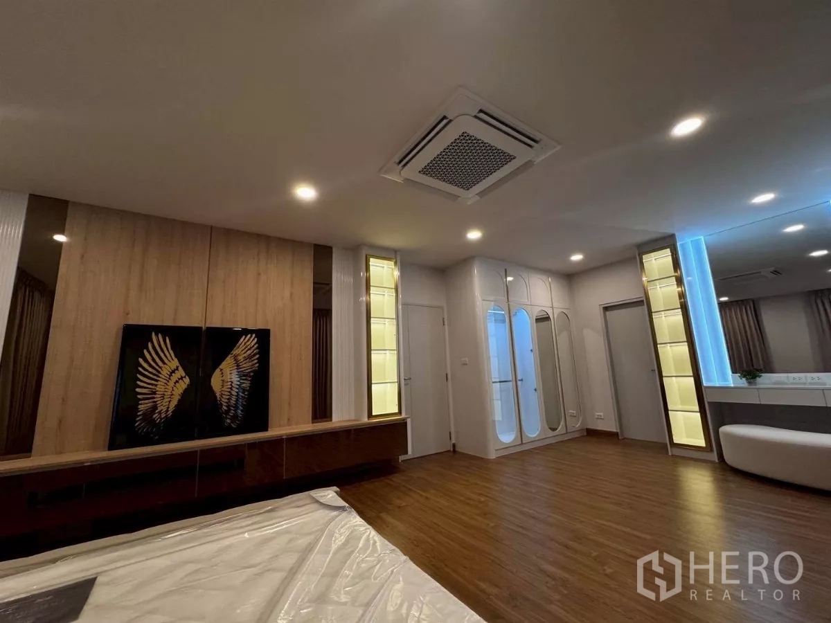 独立式住宅 出租在Bang Phli, Samut Prakan - 主套房一角，镜面衣柜、装饰墙与嵌灯点缀。