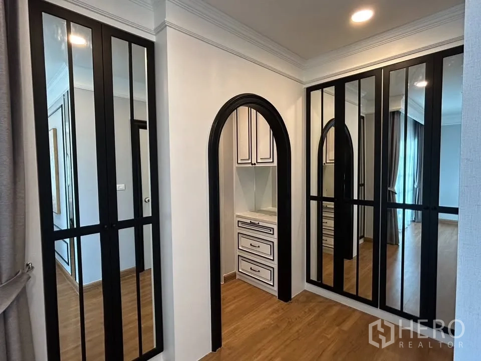 Detached House for rent in Bang Phli, Samut Prakan - Walk-in closet corridor with mirrored wardrobe doors and arched doorway to a vanity area.