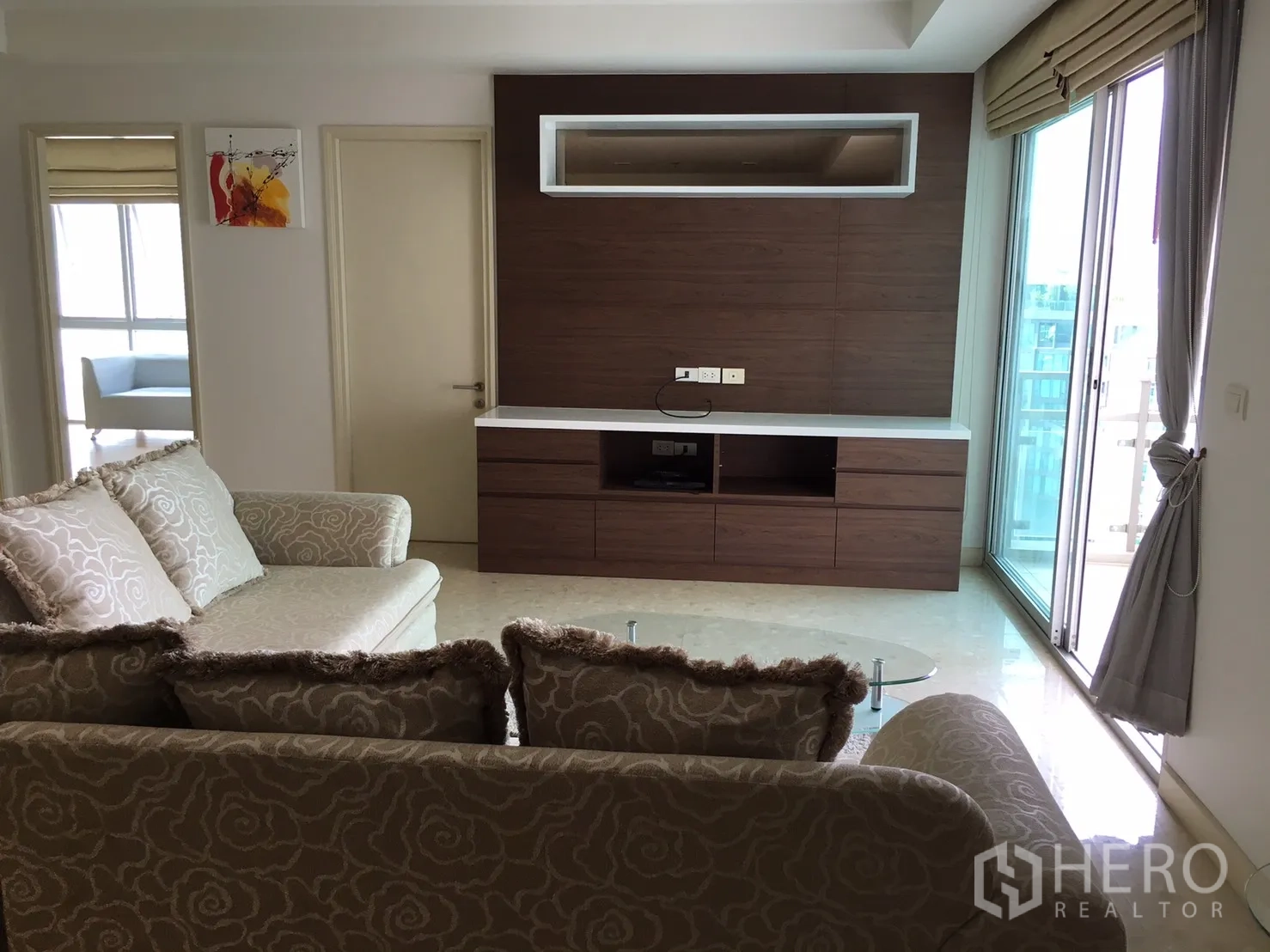 คอนโด ให้เช่าหรือขายในKhlong Toei, Bangkok - ห้องนั่งเล่นสว่าง โซฟาลาย ผนังบิลท์อินไม้ และประตูกระจกออกระเบียง