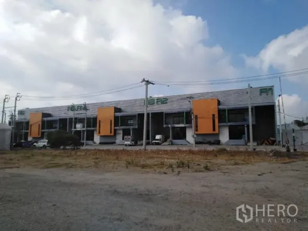 工厂 出租在Samut Prakan - 多间仓库外立面全景，前方有停车区与电线杆，天气晴朗。