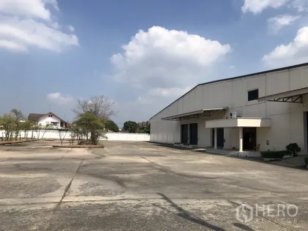 货栈 出租在Lam Luk Ka, Pathum Thani - 巴吞他尼Lam Luk Ka宽阔混凝土院场与白色仓库外立面，带装卸口