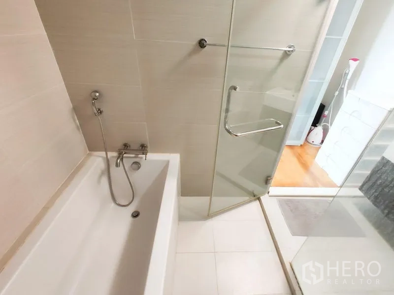 คอนโด ให้เช่าในKhlong Toei, Bangkok - มุมใกล้ของอ่างอาบน้ำและประตูกระจกใสของห้องอาบน้ำ พร้อมฝักบัวมือถือ