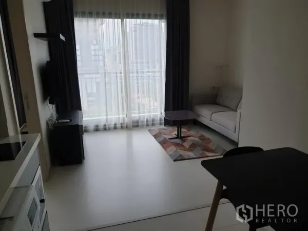 คอนโด ให้เช่าในKhlong Toei, Bangkok - ห้องนั่งเล่นสว่างด้วยหน้าต่างเต็มบาน ผ้าม่านสองชั้น โซฟาสีเทา และโต๊ะกลาง พร้อมวิวเมือง ในคอนโดใกล้ BTS ทองหล่อ เขตคลองเตย