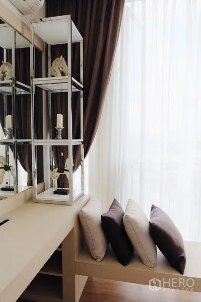Condominium for sale in Watthana, Bangkok - Window seating nook with cushions, mirrored display shelves and soft daylight.
