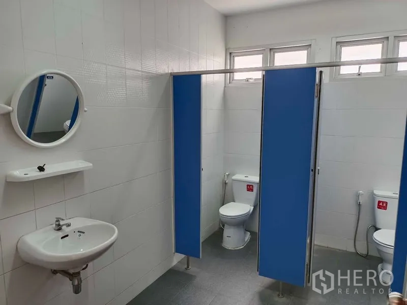 Warehouse for rent in Suan Luang, Bangkok - Clean staff restrooms with partitioned stalls, toilets, basin, and windows.
