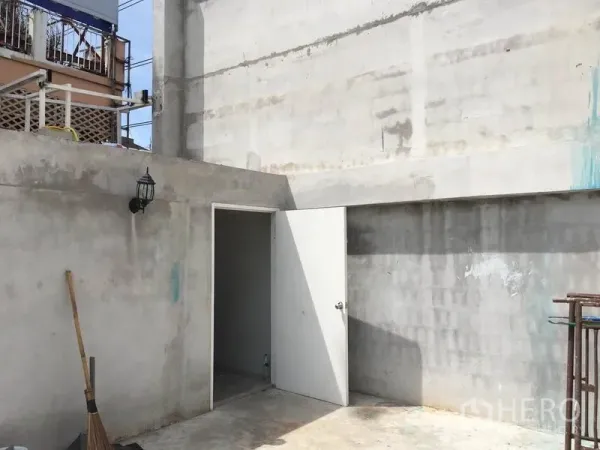 零售空间 出租在Huai Khwang, Bangkok - 混凝土后场服务区，白色门通向储物间，带室外壁灯。