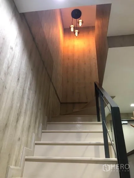 Condominium for rent or sale in Phra Khanong, Bangkok - Internal staircase with warm pendant lighting and wood-grain walls.