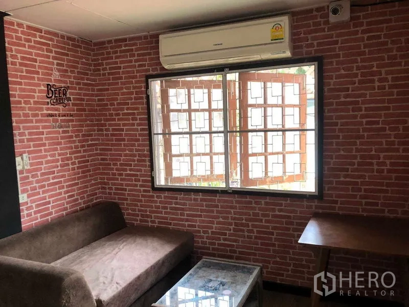 บ้าน ขายในWang Thonglang, Bangkok - ห้องพักผ่อนผนังลายอิฐ หน้าต่างติดเหล็กดัด โซฟา และเครื่องปรับอากาศ