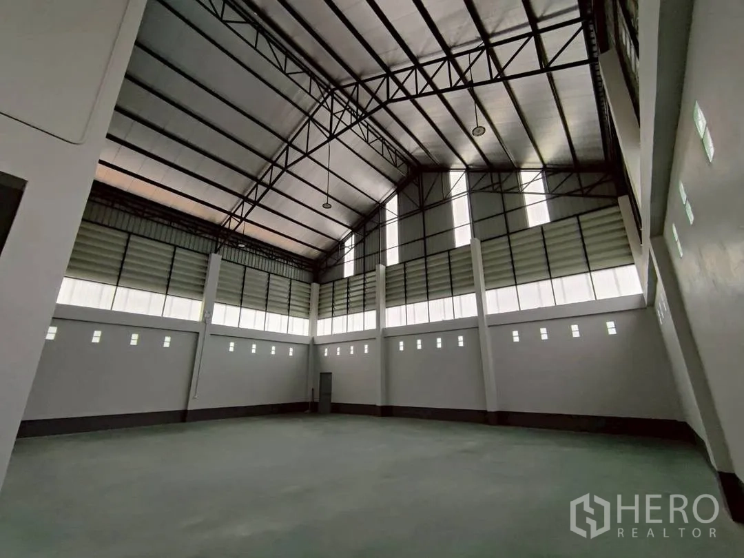工厂 for rent in Krathum Baen, Samut Sakhon - 仰视仓库的钢结构屋顶与高墙，配多扇高位小窗。