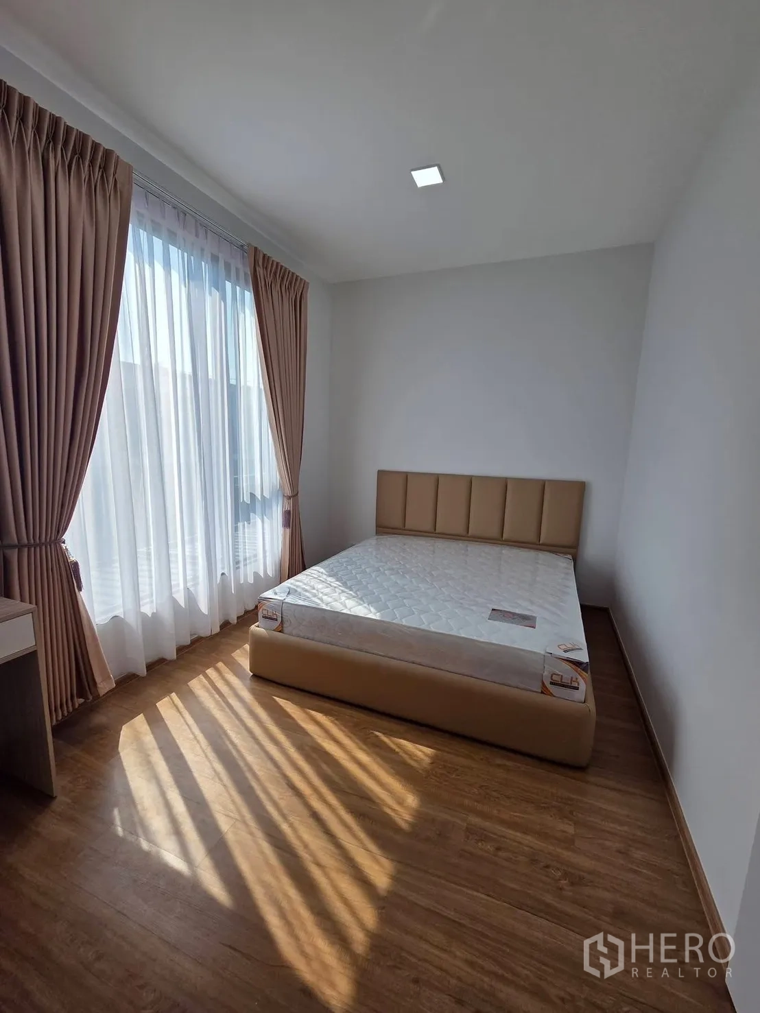 Townhouse for rent in Bang Phli, Samut Prakan - Primary bedroom with large window, sheer and blackout curtains, and upholstered bed.