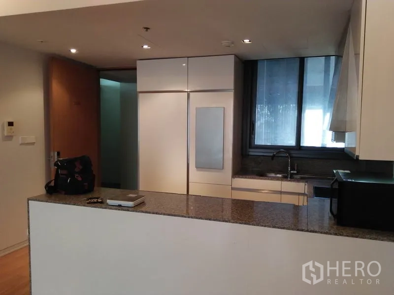 Condominium for rent in Sathon, Bangkok - Sleek kitchen with granite countertop, built-in refrigerator, sink and a window.