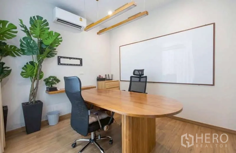 独立式住宅 出租或出售在Lat Phrao, Bangkok - 书房配长木桌、白板与绿植盆栽。