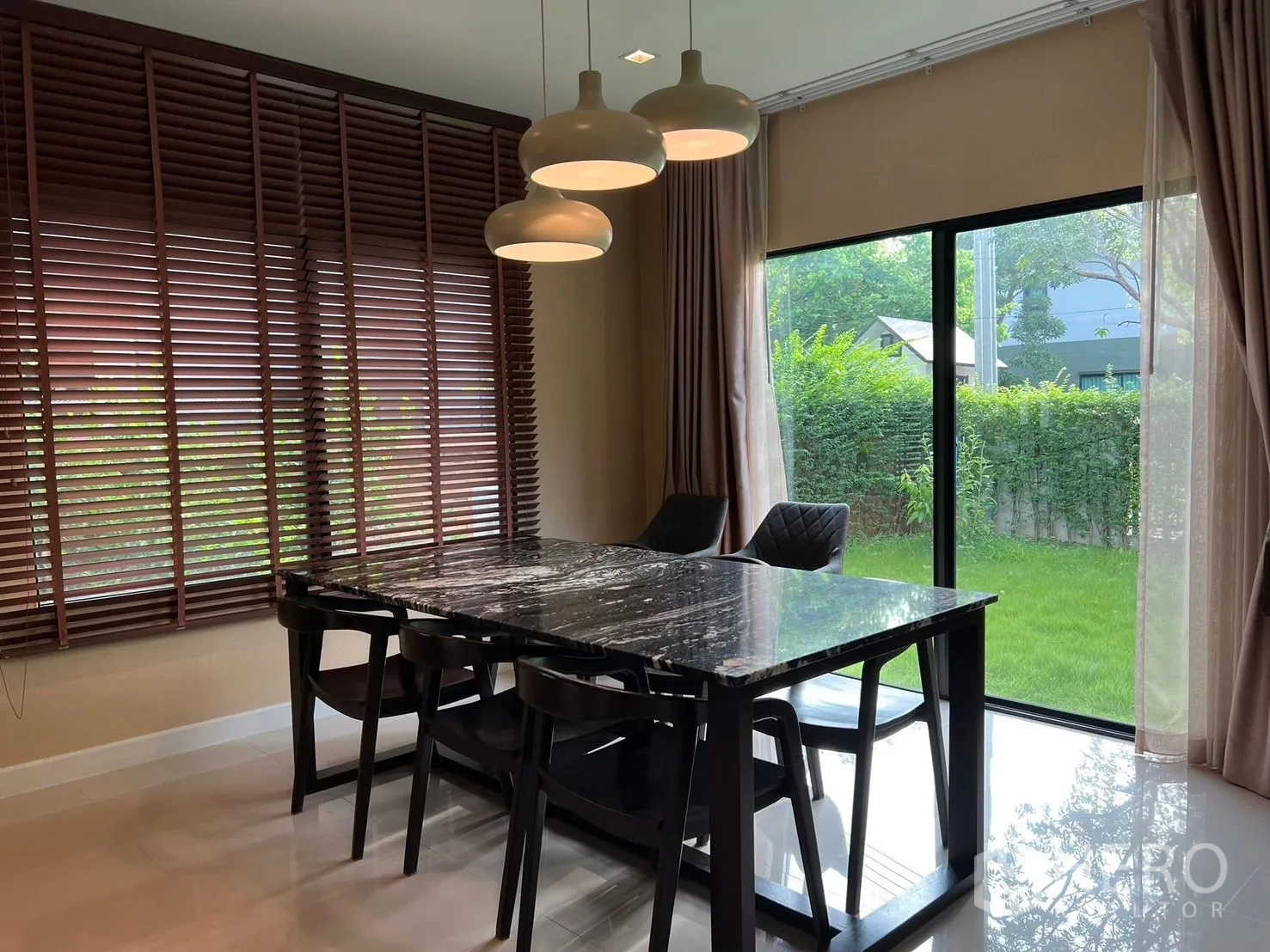 Detached House for rent in Bang Phli, Samut Prakan - Close-up of dining space with sliding glass doors opening to a green lawn and hedge.