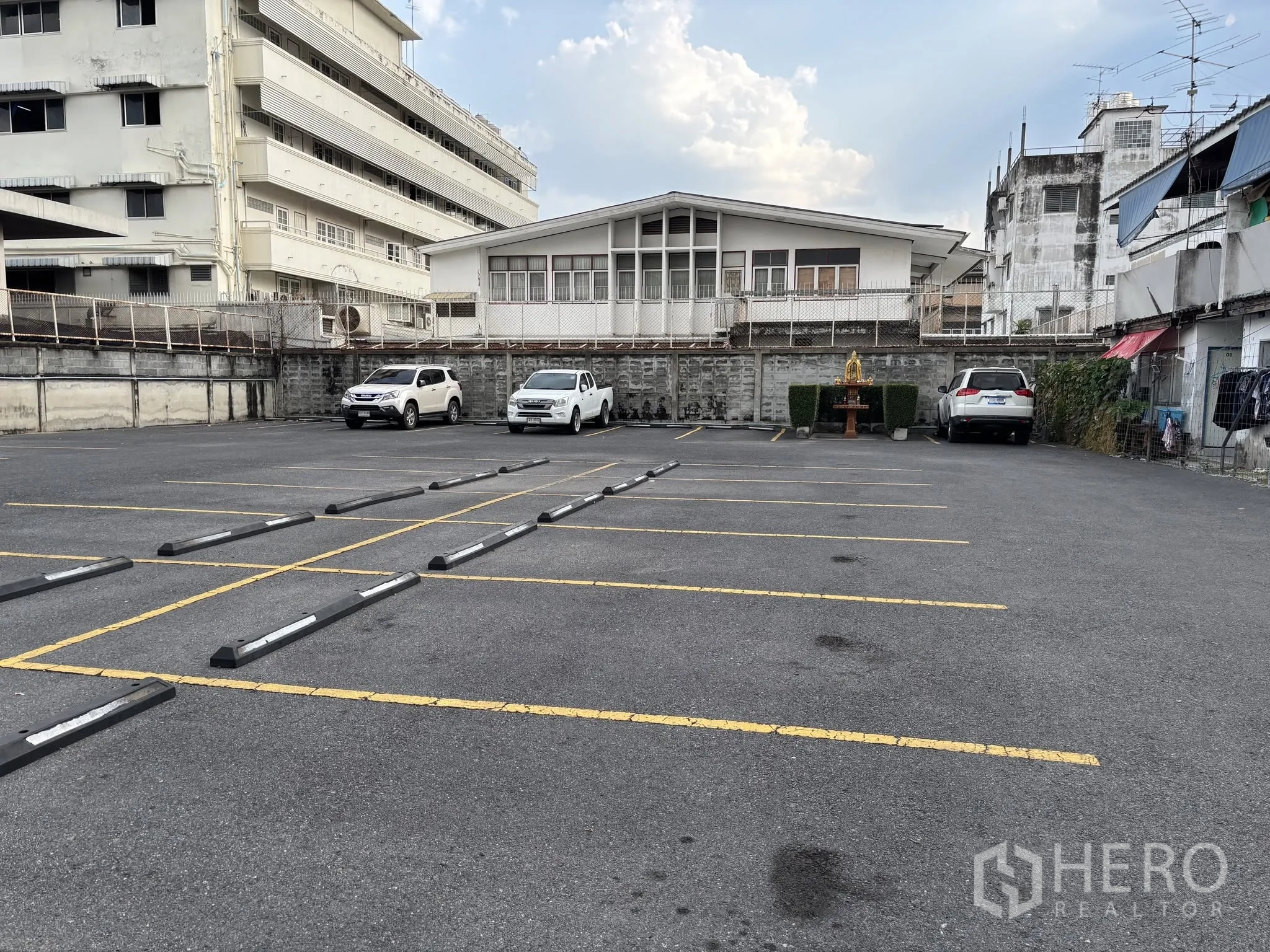 Land for rent in Sathon, Bangkok - Paved open parking lot with marked bays, wheel stops, and surrounding low-rise buildings.