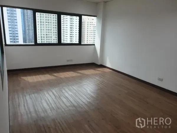 Office Space for rent in Khlong Toei, Bangkok - Sunlit corner office with wood flooring and wide windows overlooking the Bangkok skyline in Khlong Toei.