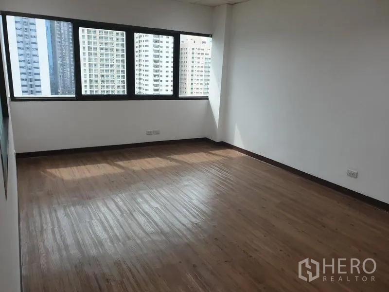 Office Space for rent in Khlong Toei, Bangkok - Sunlit corner office with wood flooring and wide windows overlooking the Bangkok skyline in Khlong Toei.