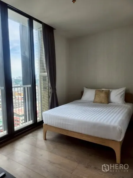 Condominium for rent in Khlong Toei, Bangkok - Primary bedroom with queen bed, tall curtains and floor‑to‑ceiling windows overlooking the Bangkok skyline.