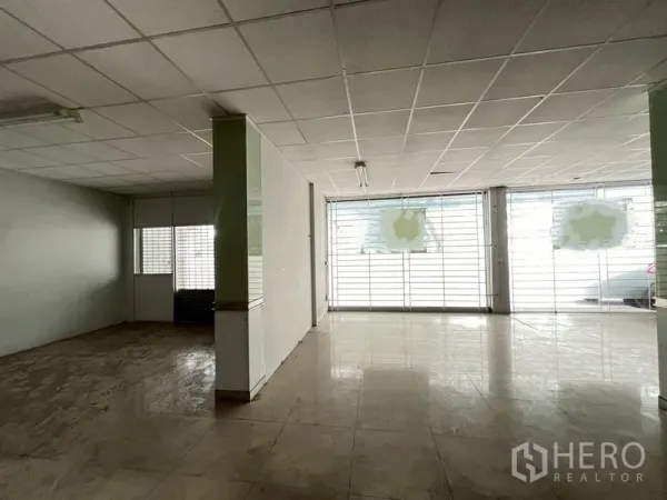 店屋 出租在Phra Khanong, Bangkok - 一层店面大厅，地砖，宽大玻璃门面与金属栅栏。