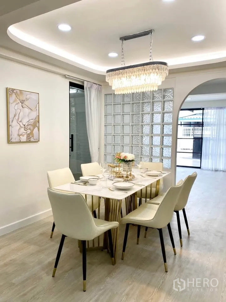 独栋房屋 for rent in Huai Khwang, Bangkok - 餐厅配大理石纹餐桌六椅、枝形吊灯与玻璃砖墙。