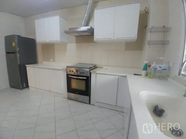 公寓 出租或出售在Watthana, Bangkok - 独立厨房，白色橱柜、烤箱与抽油烟机，墙地面为瓷砖。