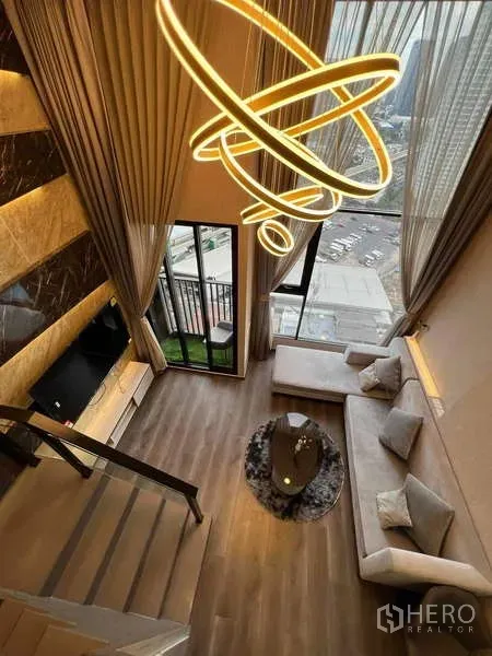 คอนโด ขายในChatuchak, Bangkok - มุมมองจากชั้นลอยลงสู่ห้องนั่งเล่น เพดานสูง โคมไฟดีไซน์ ระเบียง และวิวเมือง