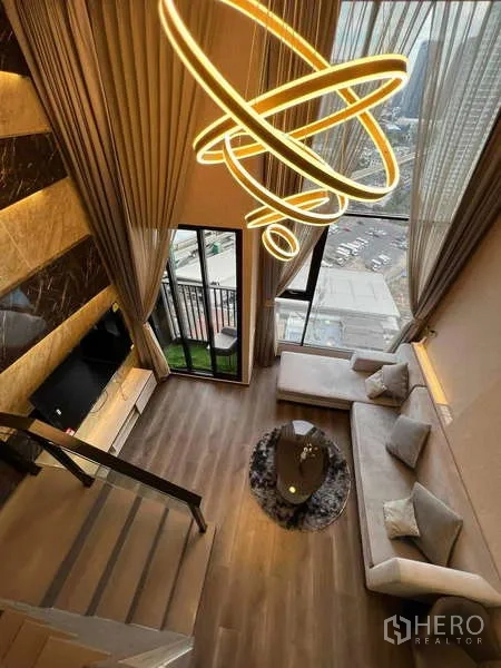 คอนโด ขายในChatuchak, Bangkok - มุมมองจากชั้นลอยลงสู่ห้องนั่งเล่น เพดานสูง โคมไฟดีไซน์ ระเบียง และวิวเมือง