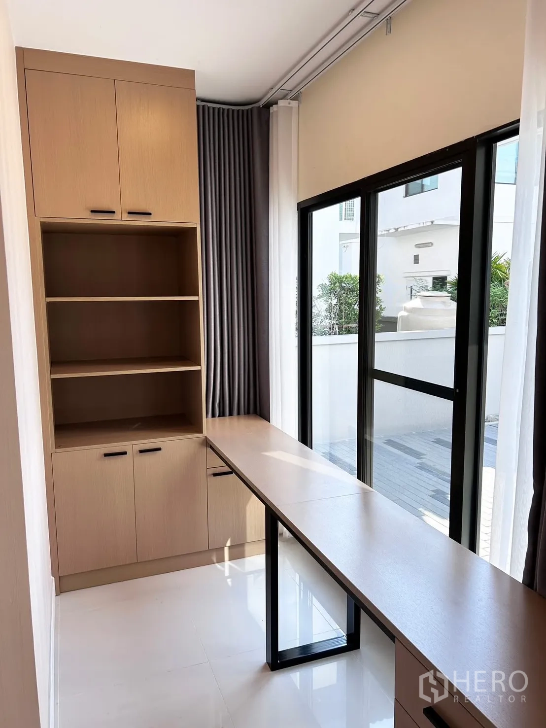 Detached House for rent or sale in Prawet, Bangkok - Compact home office with a long built-in desk, storage cabinets and a sliding glass door to the patio.