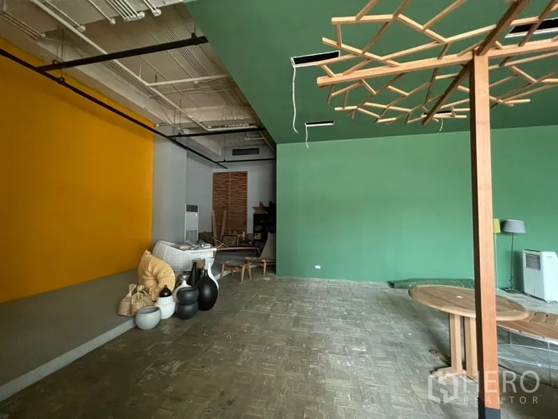 零售空间 出租在Khlong Toei, Bangkok - 开放式空间，黄绿撞色墙面与装饰道具，天花设备外露。