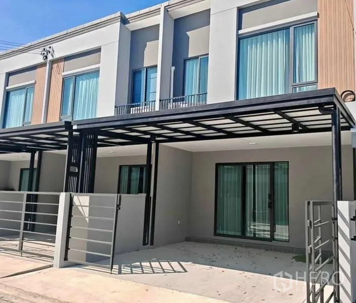 ทาวน์เฮาส์ ให้เช่าในBang Phli, Samut Prakan - ด้านหน้าทาวน์เฮ้าส์สมัยใหม่ พร้อมที่จอดรถมีหลังคา ประตูกระจกบานเลื่อน และรั้วหน้าบ้าน