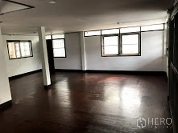 Detached House for rent in Suan Luang, Bangkok - Spacious living area with dark wood flooring and multiple windows.