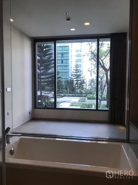 Condominium for rent or sale in Watthana, Bangkok - Bathtub view toward floor-to-ceiling window overlooking landscaped garden courtyard
