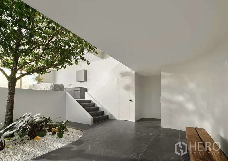 Home Office for sale in Chatuchak, Bangkok - Ground‑floor courtyard with mature tree, black stone flooring and steps to a utility area.