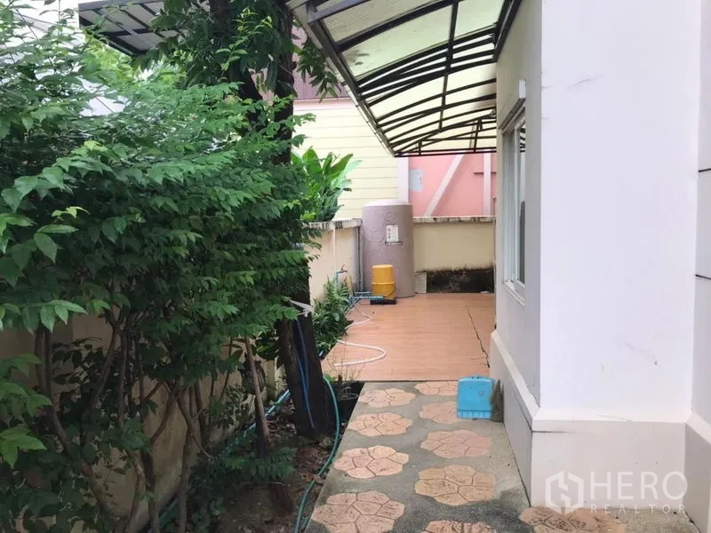 独立式住宅 出租在Bang Khen, Bangkok - 带顶侧道，设备水箱与铺装小径，周围绿意环绕。